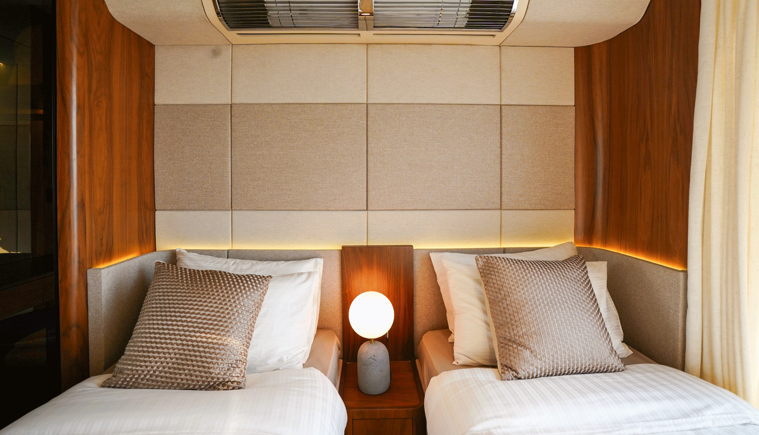 RISE 70 guest cabin with two single beds and upholstered headboard wall