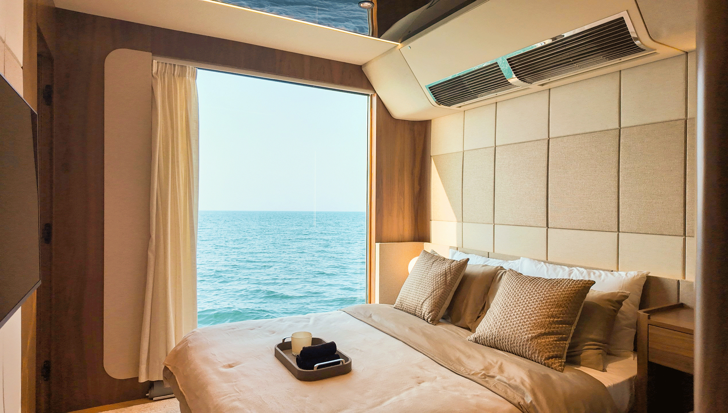 RISE 70 master suite with queen bed facing a panoramic sea window