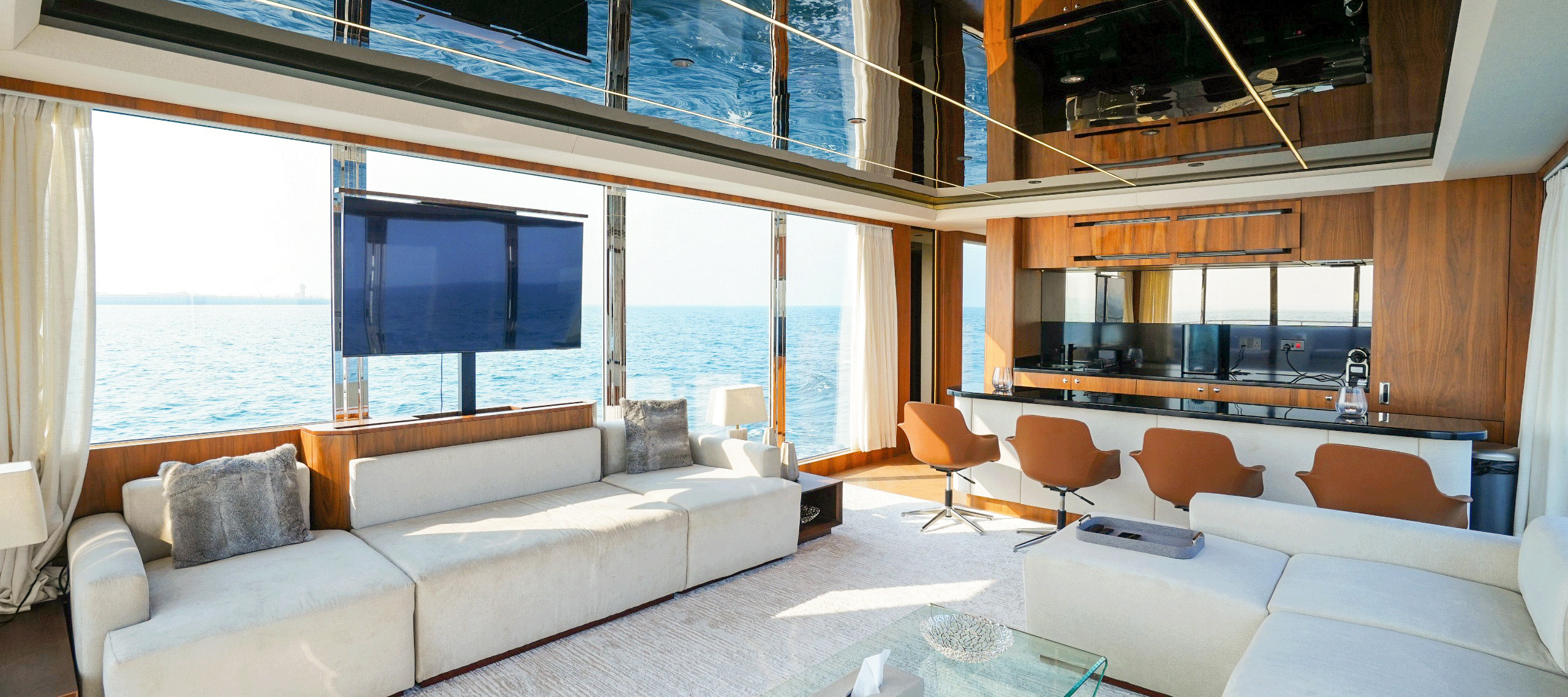 RISE 70 main saloon with wrap-around sofas, dining area and panoramic windows